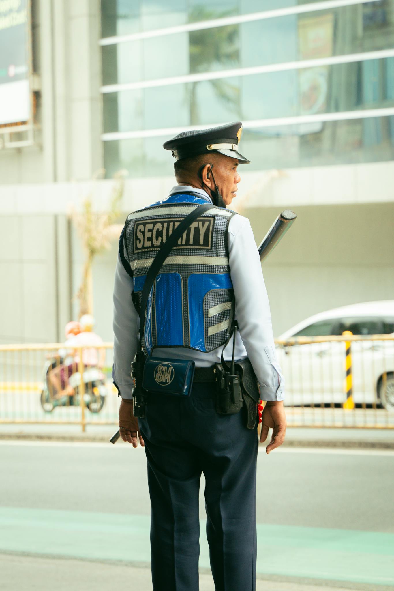 Security guard in uniform standing outdoors on a city street, maintaining public safety.