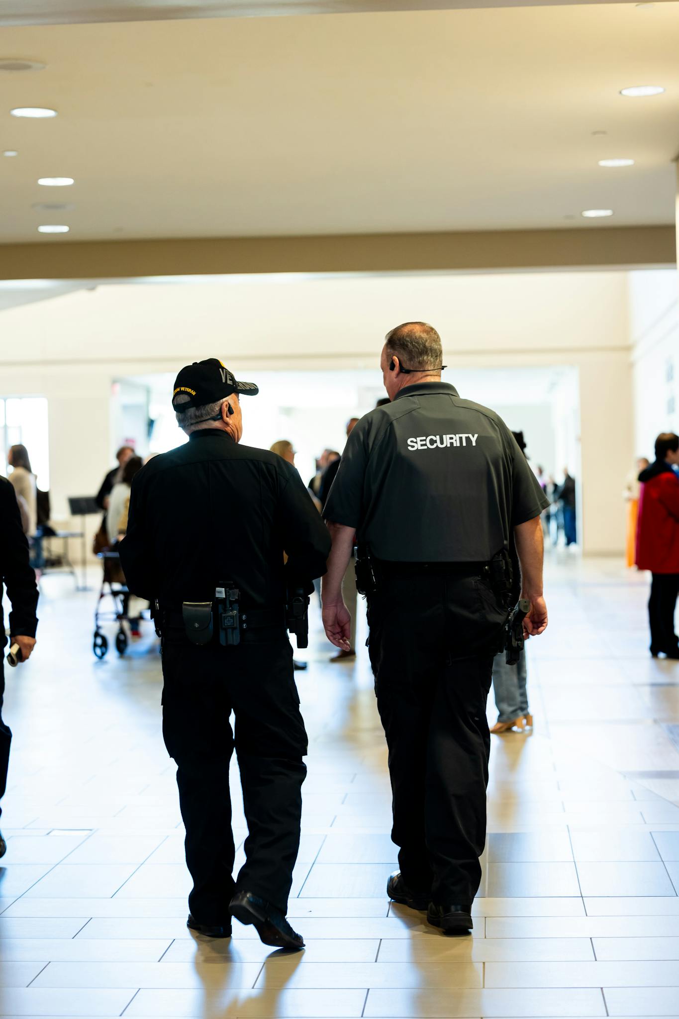 Two security guards walking indoors, ensuring safety in a busy public space.
